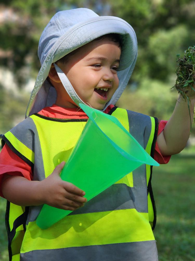 A young child examining something found outdoors during exploration at L&L Academy Lincoln Park