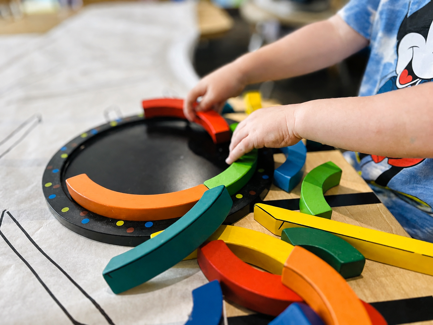 Preschool child arranging colorful wooden pieces during a classroom activity.