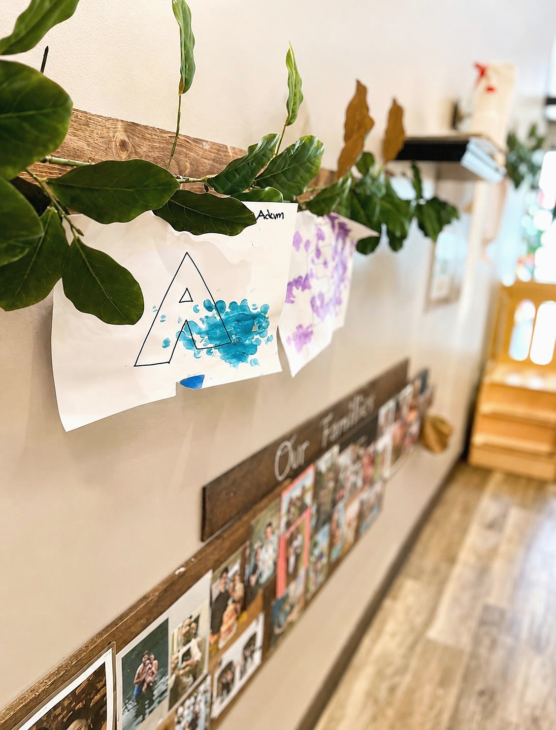 Children's artwork and classroom documentation displayed beside greenery at L&L Wicker Park.