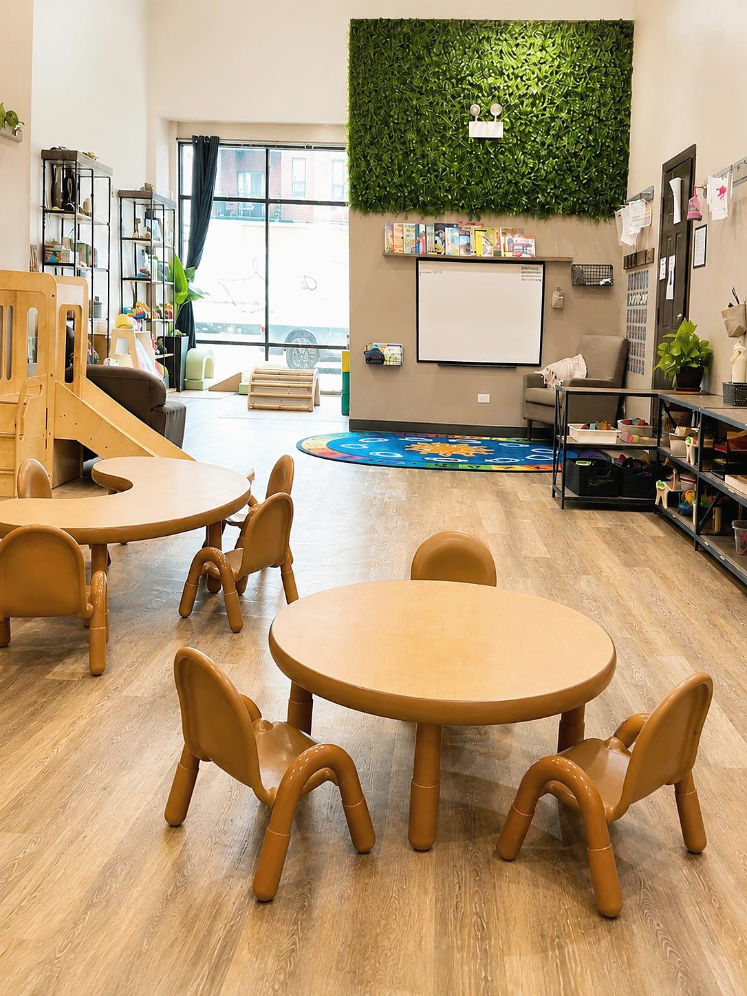 The Wicker Park classroom environment with child-sized tables, books, and an indoor play structure.